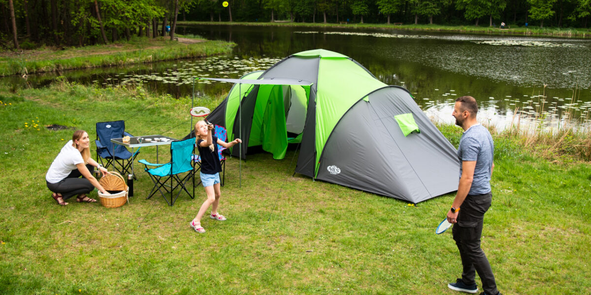 Turista s kompletnou outdoor výbavou oddychuje v prírode pri stanovaní počas večera.