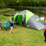 Turista s kompletnou outdoor výbavou oddychuje v prírode pri stanovaní počas večera.