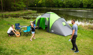 Turista s kompletnou outdoor výbavou oddychuje v prírode pri stanovaní počas večera.