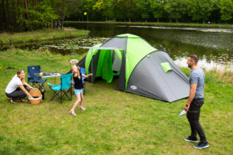 Turista s kompletnou outdoor výbavou oddychuje v prírode pri stanovaní počas večera.