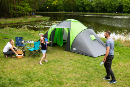 Turista s kompletnou outdoor výbavou oddychuje v prírode pri stanovaní počas večera.
