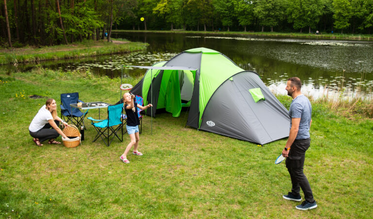 Turista s kompletnou outdoor výbavou oddychuje v prírode pri stanovaní počas večera.