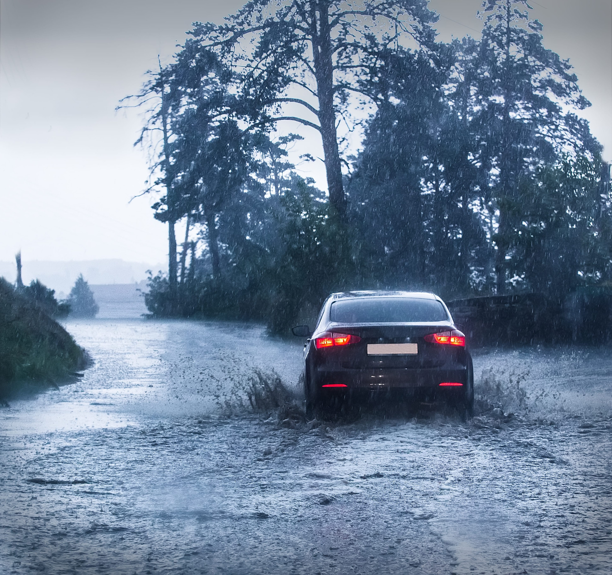 Osobné auto počas silnej búrky a intenzívneho dažďa na ceste.